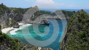 Aerial drone zooming view of tropical beach, sea rocks, turquoise ocean and palm trees. Atuh beach, Nusa Penida island