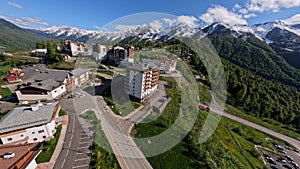 Aerial dynamic view flying over village alpine resort sunny infrastructure snowy mountain peaks