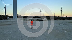 Aerial of engineer with laptop inspecting and control the efficiency of windmill