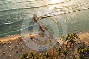 Aerial, evening view of Waikiki Beach ocean waves bathing in a sunset light