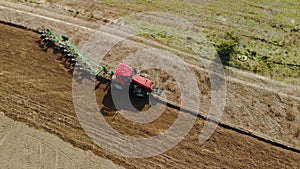 Aerial: farmer on tractor with a revolving multi-field plow on the arable land processing the field