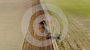 Aerial: farmer on tractor with a revolving multi-field plow on the arable land processing the field