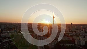 AERIAL: Flight over Berlin, Germany at beautiful Sunset, Sunlight and view on Alexanderplatz TV Tower, Sunflairs