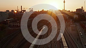 AERIAL: Flight over Berlin, Germany Ostbahnhof Central Train Station with ICE Train driving at beautiful Sunset