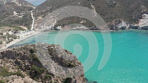 Aerial flight over dry Island in SUmmer heat revealing Turquoise Blue Ocean with Rocky Cliff Coast in Milos, Greece