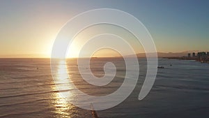 Aerial flight over the ocean at sunset. The drone flies into the distance against the backdrop of a sunny path. View of