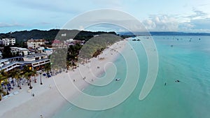 Aerial flight over sandy beach, waves and tourists