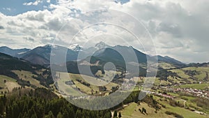 Aerial flight over spring landscape with clouds moving over mountains time lapse. Pan left to right