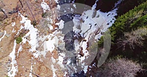 Aerial flight overhead over river creek in yellow mountain and forest fall establisher. Outdoor snow wild nature scape in