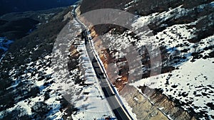 Aerial flight in winter landscape. cars driving in winter on a snowy road between the mountains. Italy mountain trip