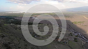 Aerial Flyby View on the Maasai village in on the coast of Natron Lake front of the Ol Doinyo Lengai, Mountain of God in