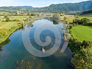 AERIAL: Flying above a group of friends cruising in a canoe along a calm river.