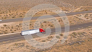 AERIAL: Flying above a red cargo truck enduring a long drive across Utah desert.