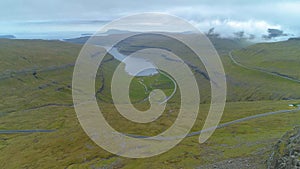 AERIAL: Flying above road meandering down the rugged terrain of Faroe Islands.