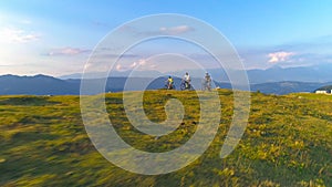 AERIAL: Flying along group of mountain bikers pedalling uphill on sunny morning