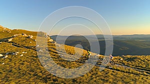 AERIAL: Flying along sporty couple pedalling their bicycles up a grassy hill.