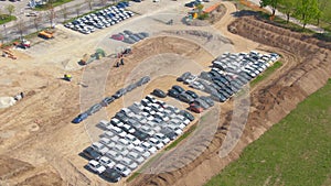 AERIAL: Flying around a large construction site serving as a parking lot.