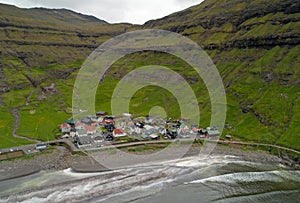 AERIAL: Flying away from a small coastal town right next to an empty black beach