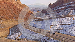 AERIAL: Flying behind a lorry hauling cargo across a wintry canyon in Utah.