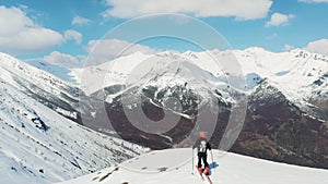 Aerial: flying over hiker on snowy mountain top, ski touring mountaineering snow mountain, panoramic view on the alps, conquering