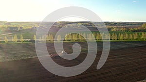 Aerial Flying Over Rural Village Fields Where Agriculture Tractor Plows The Land