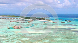 AERIAL: Flying toward an island in the Maldives with abandoned overwater villas.