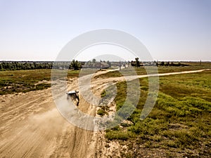 Aerial flying view of off road 4x4 truck vehicle moving on a dusty field d