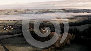 Aerial footage of ancient Northumberland castle with temperature inversion cloud