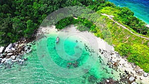 Aerial footage of a beach with turquoise colored water swashing on the shoreline