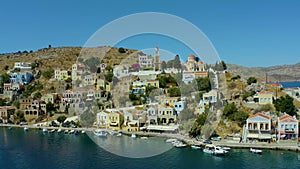 Aerial footage of the beautiful greek island of Symi Simi with Colourful houses and small boats at heart of the island