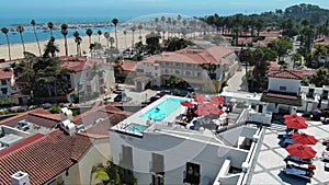 aerial footage of buildings with a rooftop pool, lush green palm trees, blue ocean water with boats and yachts docked