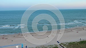 aerial footage of the Carolina Beach Boardwalk with a Ferris wheel, colorful amusement rides, people walking, a sandy beach