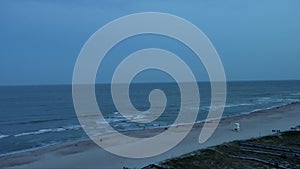 aerial footage of the Carolina Beach Boardwalk with a Ferris wheel, colorful amusement rides, people walking, a sandy beach