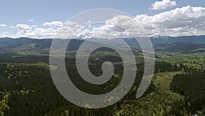 Aerial footage of carpathian forests on a Yablunivskiy pereval with a view on Hoverla and Pip Ivan mountains on a horizon,