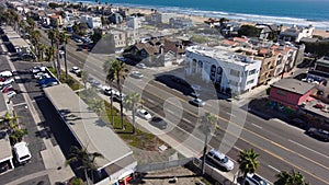 aerial footage of cars and trucks driving on the street with palm trees, homes, apartments blue ocean water and a sandy beach