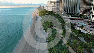 aerial footage of the coast of the Atlantic ocean with hotels and luxury condominiums in the city skyline at sunrise, palm trees