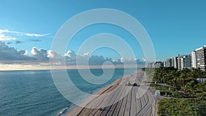 aerial footage of the coast of the Atlantic ocean with hotels and luxury condominiums in the city skyline at sunrise, palm trees