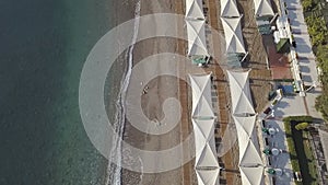 Aerial footage of coast line with umbrellas on sandy beach