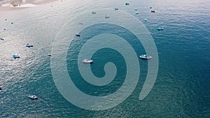 Aerial footage of colourful wooden fisherman boats on the ocean near beach