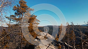 aerial footage couple hikers standing on top of cliff with raised arms. man and woman travelers enjoying great view in