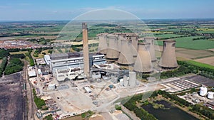 Aerial footage of the Eggborough Power station showing the eight cooling towers and chimneys along side farmers fields on a bright