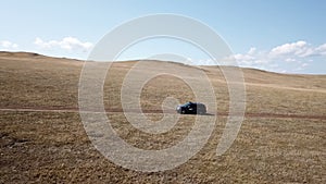 Aerial footage filmed with drone of pickup car riding on the siberian steppe.