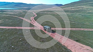Aerial footage filmed with drone of pickup car riding in steppe. The car travels along the steppe to siberia, roads laid