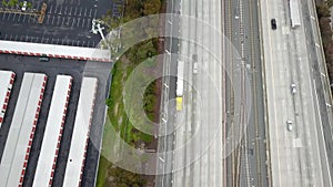 Aerial footage of a free way with cars and trucks driving on the road surrounded by lush green trees, grass and plants in Pasadena