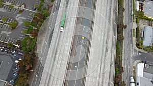 Aerial footage of a free way with cars and trucks driving on the road surrounded by lush green trees, grass and plants in Pasadena