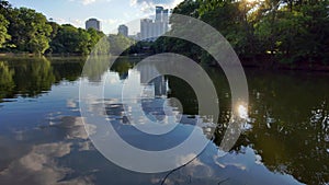 aerial footage of of a gorgeous summer landscape at Piedmont Park with park benches on Lake Clara Meer, lush green trees
