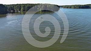 aerial footage of a gorgeous summer landscape at Proctor Landing park with green lake water, trees and grass, boats and people in