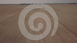 aerial footage of green combine harvesting barley in north dakota in summertime