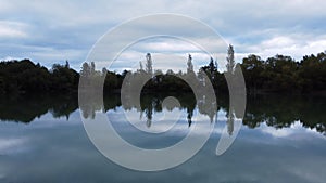 Aerial footage of a green lake with a reflection of clouds and trees