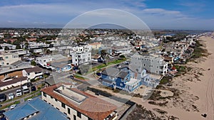 aerial footage of the homes and apartments in the cityscape with lush green palm trees and blue ocean water with cars driving